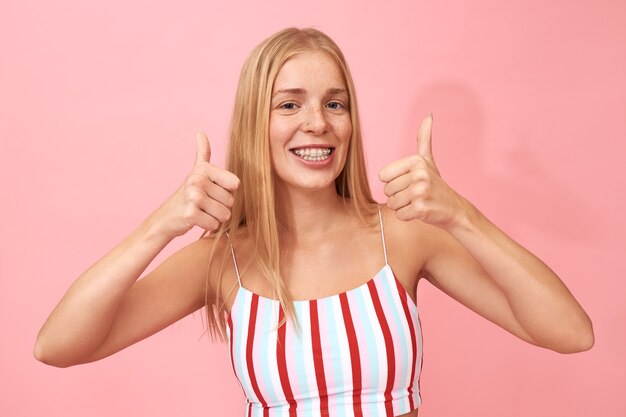 Positive optimistic teenage girl making thumbs gesture, encouraging you to click like button, being excited about good news