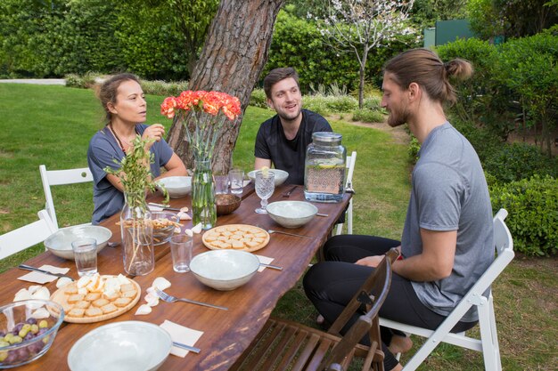 Positive people having breakfast at wooden table in backyard