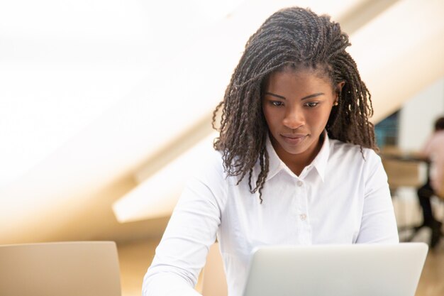 Positive serious female employee working on project