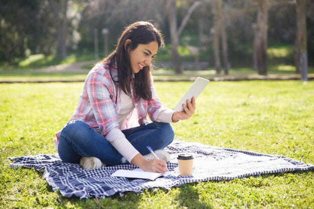 Positive student girl working on home assignment outdoors