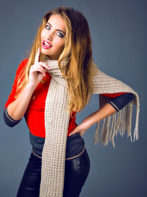 Positive studio fashion lifestyle autumn winter portrait, cheerful blonde woman playing with her scarf, smart casual outfit.