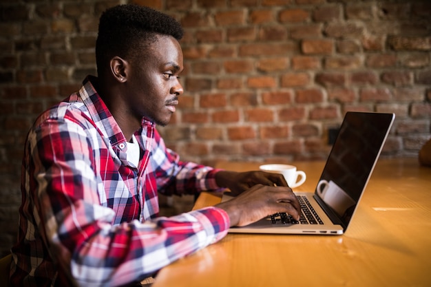 Positive stylish young Afro American copywriter chatting on laptop