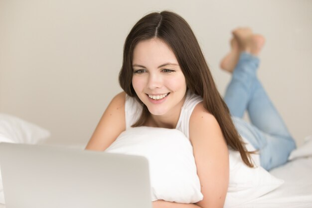 Положительная девушка покупает онлайн в постели у себя дома