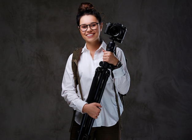 Free photo the positive traveler female holds digital photo camera and a tripod.