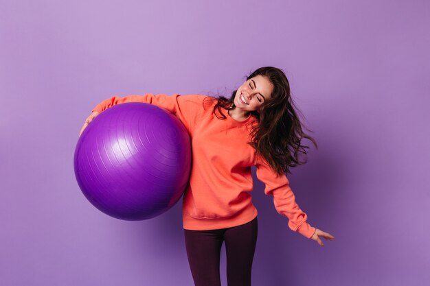 Positive woman in bright sports suit is engaged in fitness