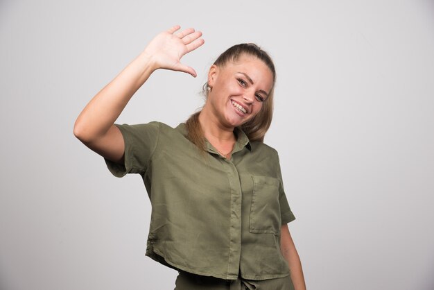 Positive woman in green sweater showing her hand.