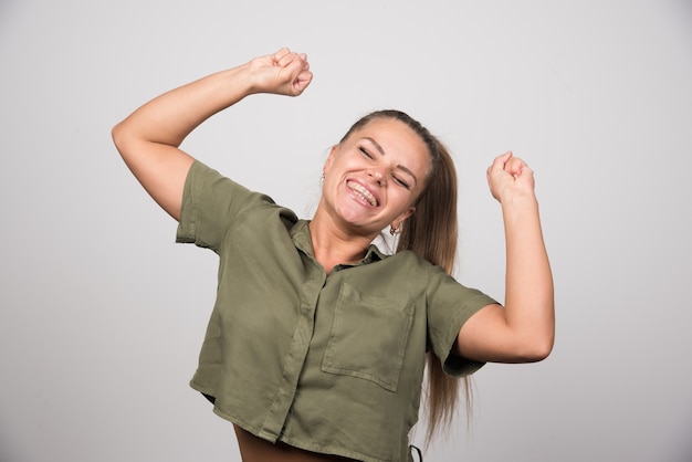 Positive woman in green sweater standing happily.