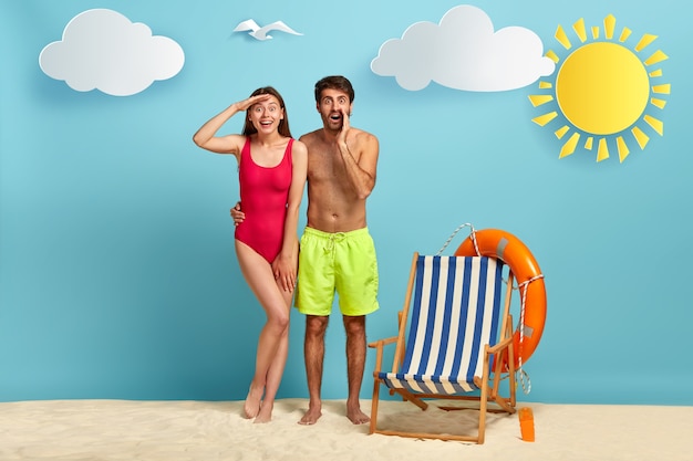 Free photo positive woman in red bikini keeps palm near forehead