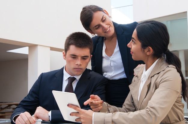 Positive woman showing tablet screen to business people