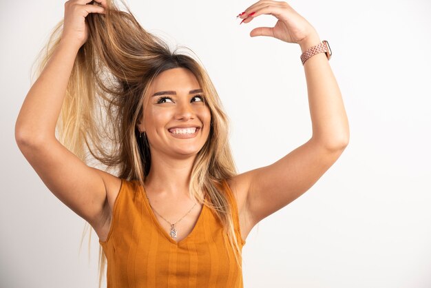 Positive woman touching her hair and posing on white background.