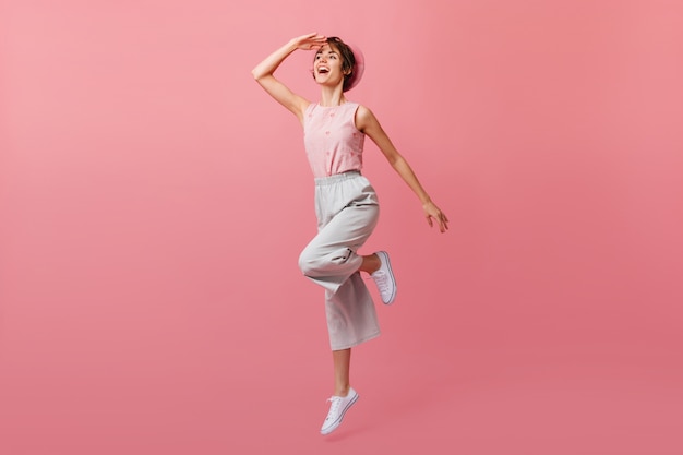 Positive woman in white shoes jumping and looking away