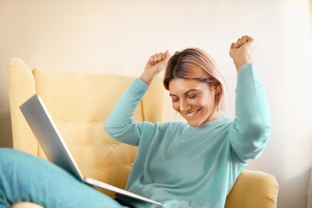 Foto gratuita la donna positiva vince un premio in internet e prova a ballare sulla sedia.