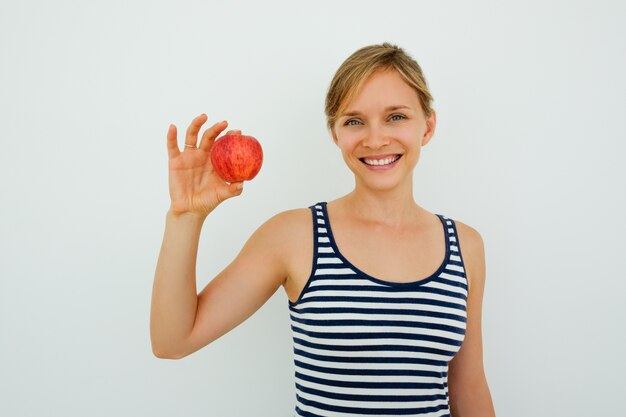Positive woman with healthy teeth showing apple
