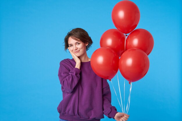 Positive young brown-eyed charming curly brunette female smiling gladly