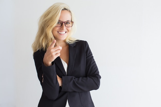 Positive young businesswoman pointing at camera