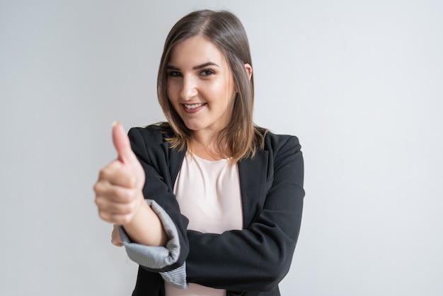 Positive young Caucasian businesswoman showing thumb up