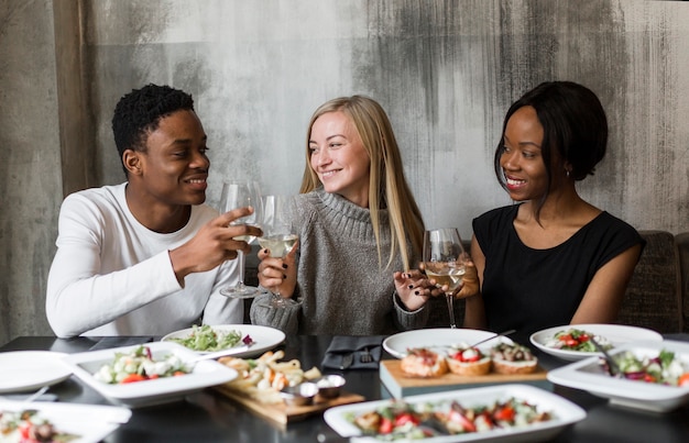 Free photo positive young friends having wine at dinner