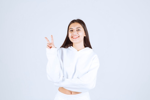 positive young girl model showing victory sign .