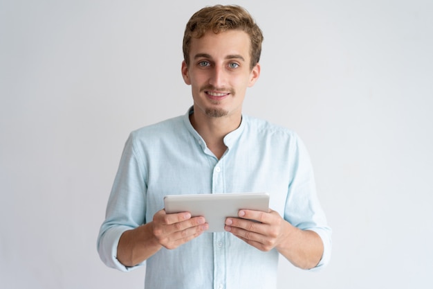 Positive young man holding tablet computer