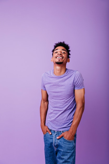 Positive young man looking up with cheerful smile. african guy in casual clothes posing.