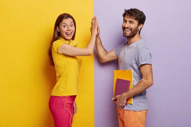 Positive young woman and man give high five, agree work as team, stand sideways