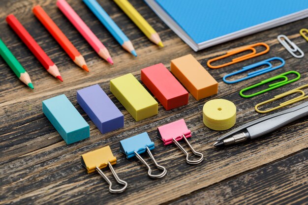 Post pandemic schooling concept with notebook, school supplies on wooden table high angle view.