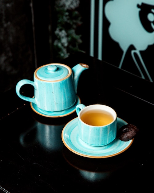 A pot and a cup of tea with side cookie