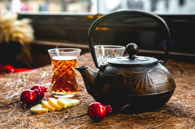 Pot of tea with glass and lemon side view