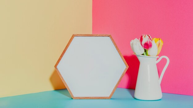 Pot with flowers near hexagon frame