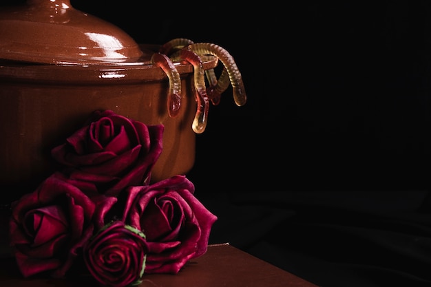 Pot with jelly and roses on black background