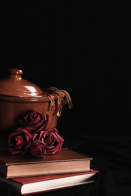 Free photo pot with roses and jelly on black background