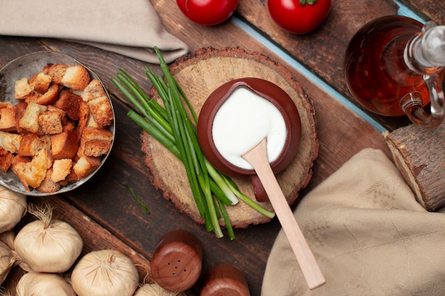 A pot of yogurt with herbs and crackers on the wooden table