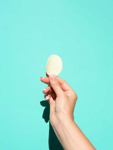 Potato chip held over colored background