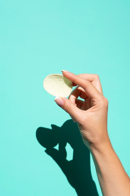 Potato chip held over turquoise background