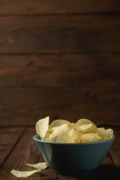 Potato chips in bowl on a wooden table.