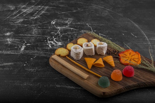 Potato chips with pastry products on a wooden platter, angle view