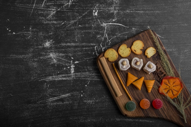 Potato chips with pastry products on a wooden platter on the bottom corner