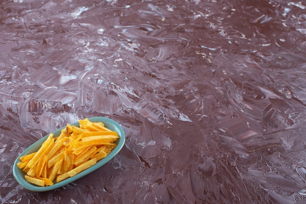 Patatine fritte in un piatto, sul tavolo di marmo.