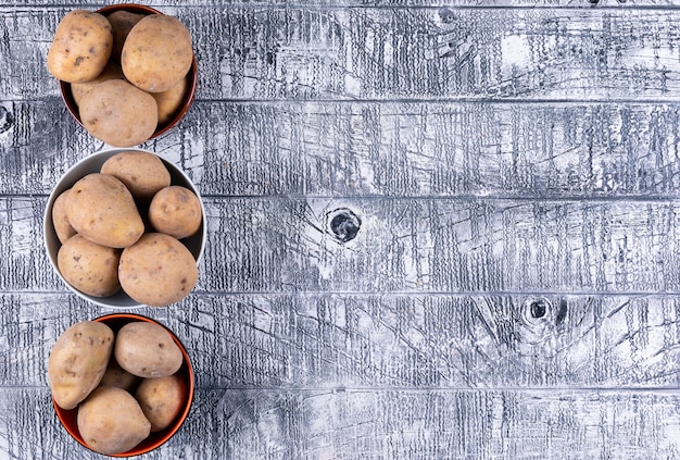 Potatoes in a bowls top view on a gray wooden table
