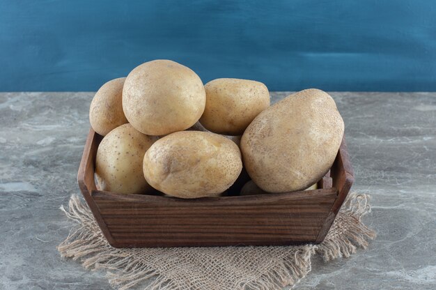 Potatoes in the box, on the towel , on the marble table. 