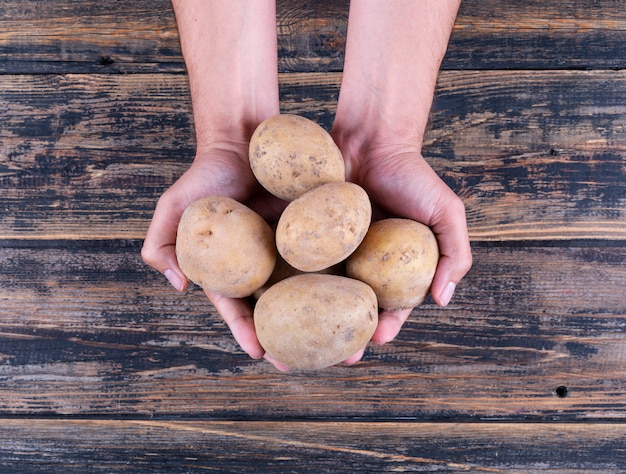 Potatoes in a man's hands on a dark wooden table