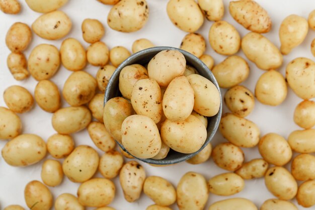 Potatoes in a mini bucket top view on a white wall