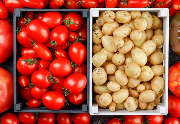 Картофель и помидоры в деревянных ящиках на томатной стене, плоское положение.