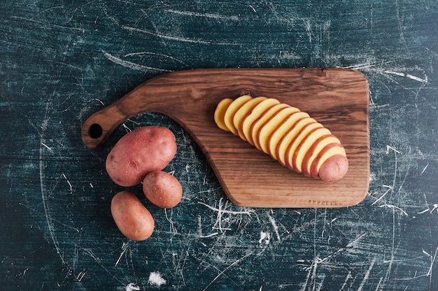 Potatoes on a wooden board and in the cup, top view.