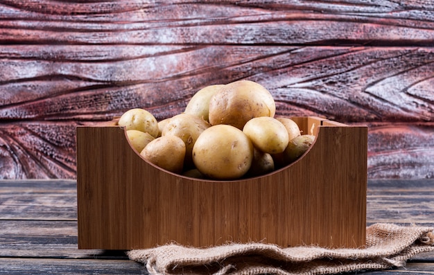 Potatoes in a wooden box on a wooden table