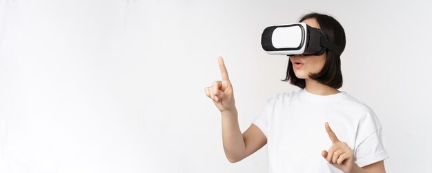 バーチャルリアリティグラスでアジアの女性のPotraitは、上に立っているvrヘッドセットでsmthを選択することを指しています...