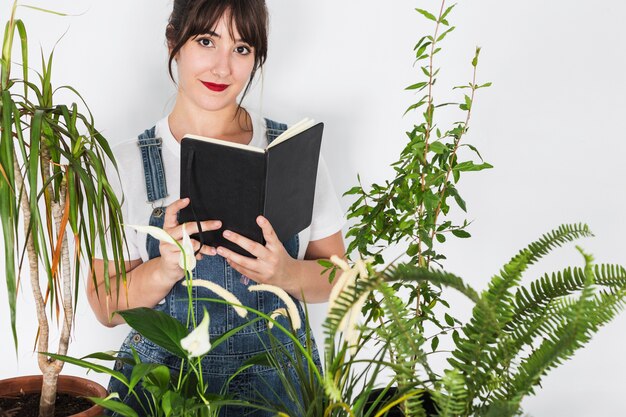 Potted plants in front of beautiful female florist holding diary