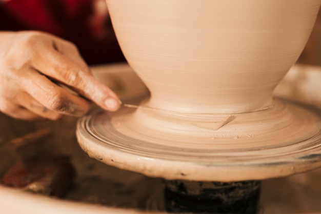 Поттер срезает готовую глиняную вазу с прялки