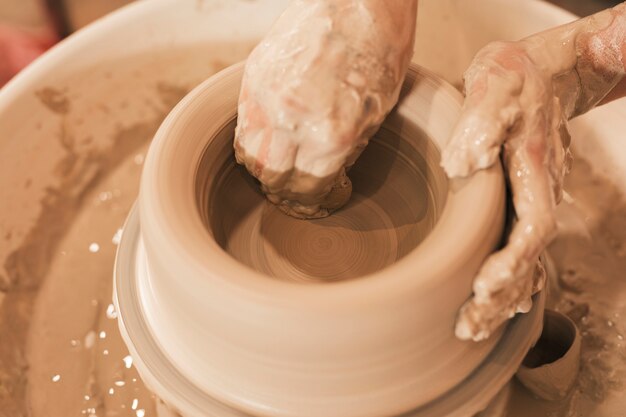 A potter's hands shaping clay on a wheel
