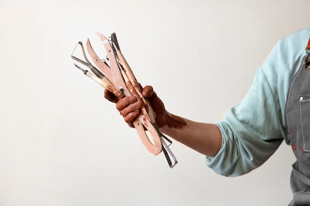 Pottery craftsperson in the studio holding tools